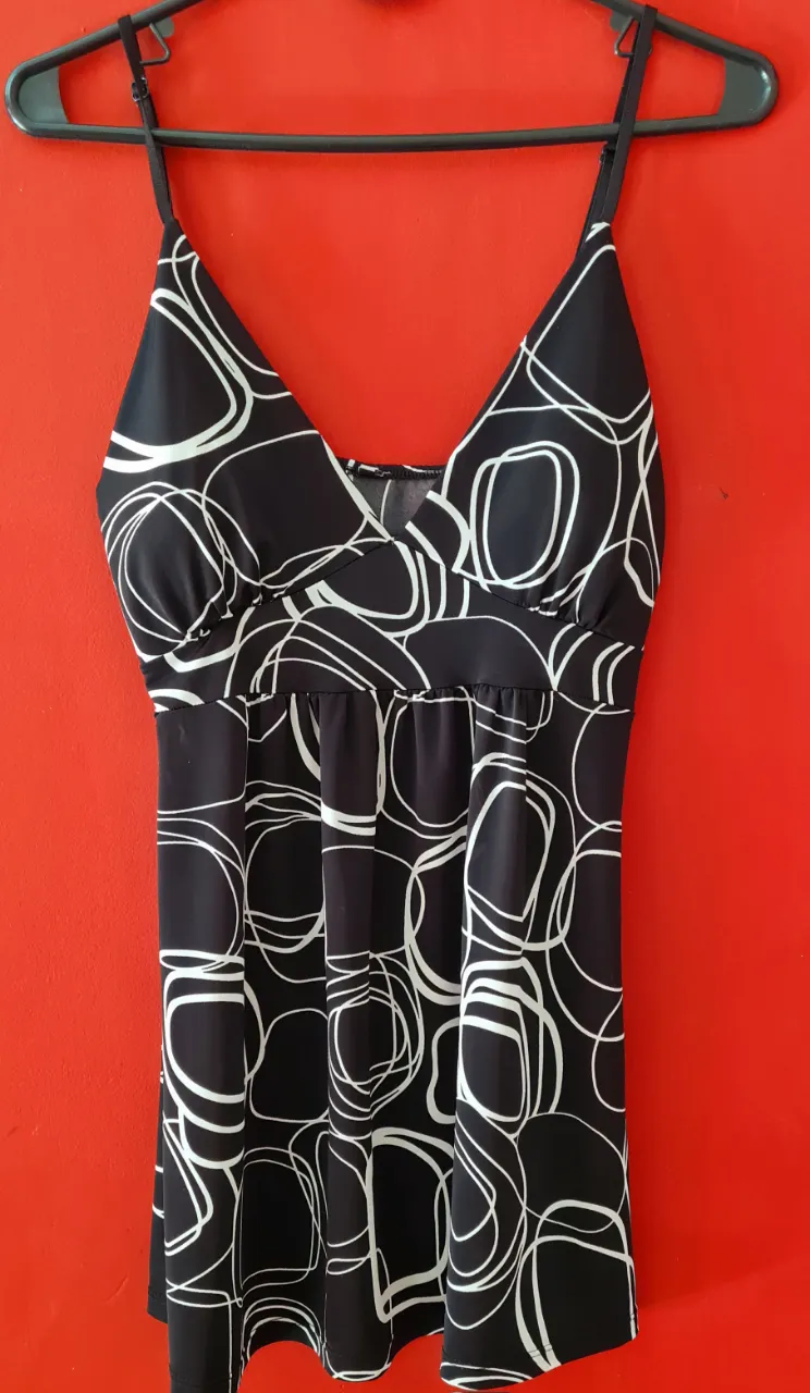 Vestido negro con estampado abstracto en blanco. Diseño con breteles finos y escote en V. Ideal para un look casual o de fiesta.