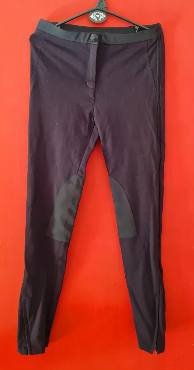 Calzas de equitación negras con detalles en cuero en las rodillas y cierre en los tobillos. Cintura alta con botón.