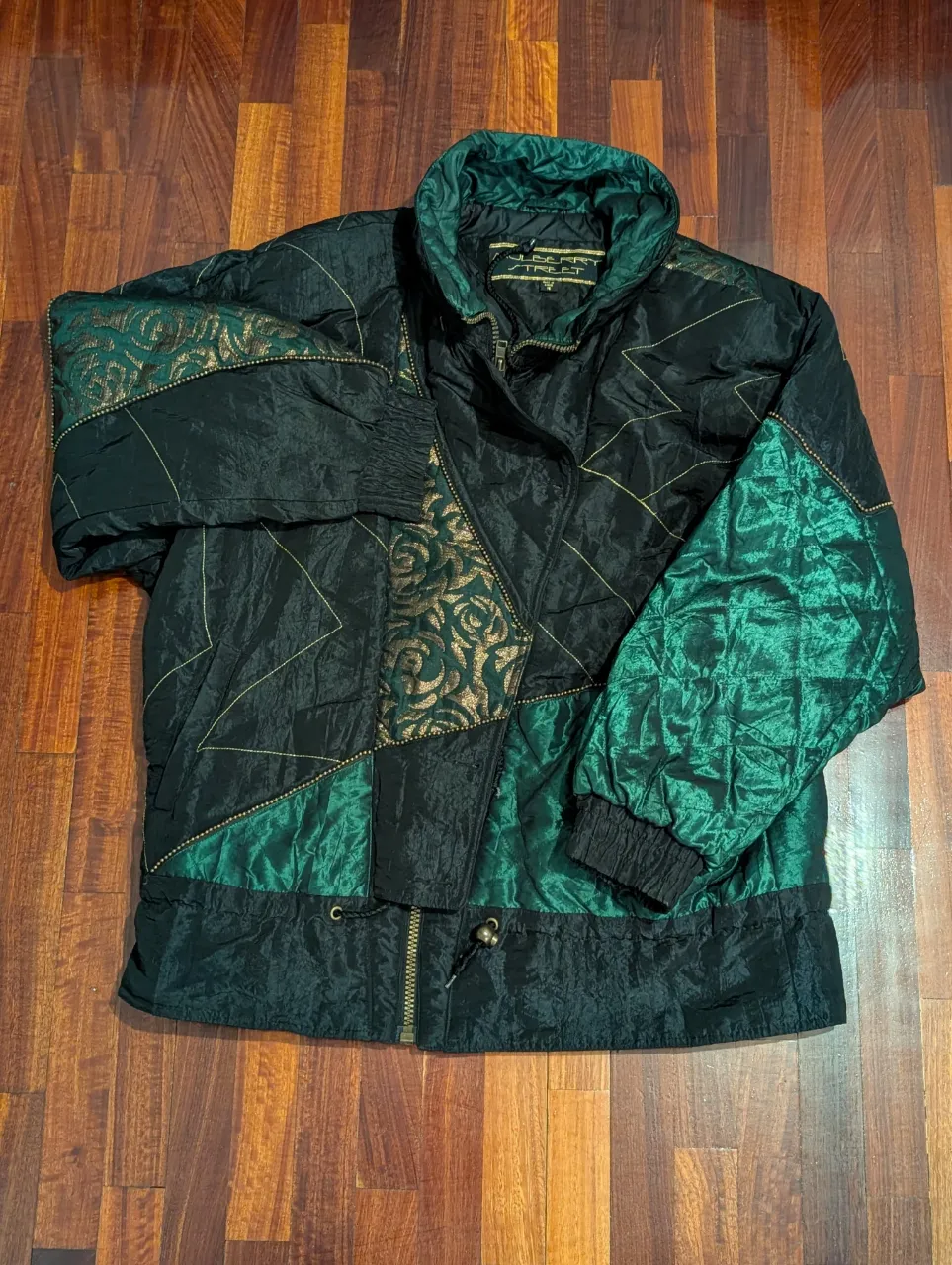 Campera vintage Mulberry Street con diseño patchwork en negro y verde, detalles dorados y puños tejidos. Ideal para un look retro y abrigado.