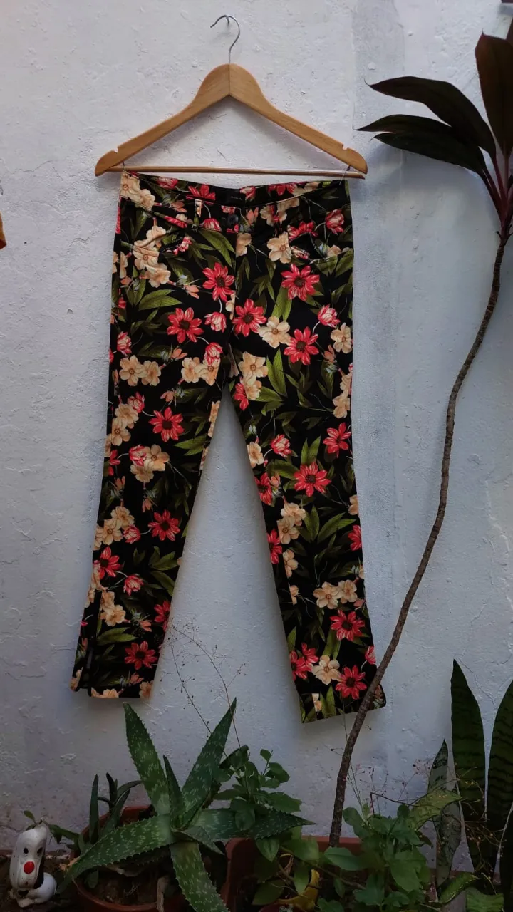 Pantalón de vestir de mujer con estampado floral en tonos rojos y beige sobre fondo negro. Corte recto, ideal para un look casual o de salida.