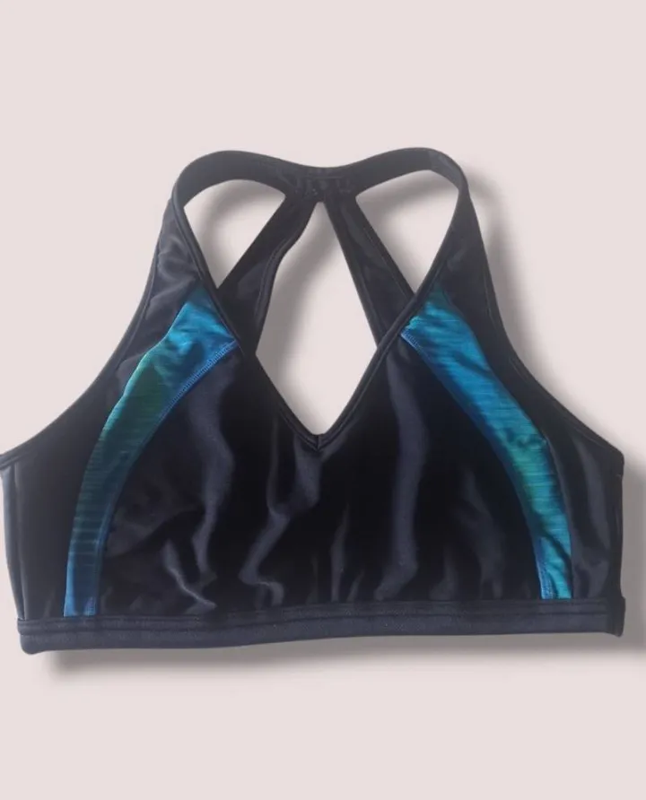 Top deportivo negro con detalles en azul y verde. Ideal para entrenamientos de alto impacto. Diseño con espalda cruzada y ajuste perfecto.