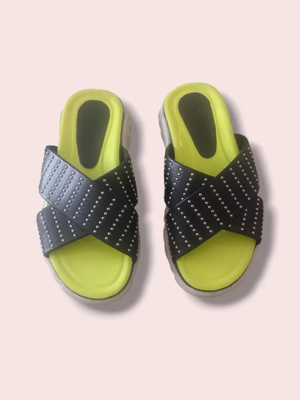 Sandalias de mujer con diseño cruzado y tachas plateadas. Suela amarilla y base blanca. Ideales para un look casual y moderno.