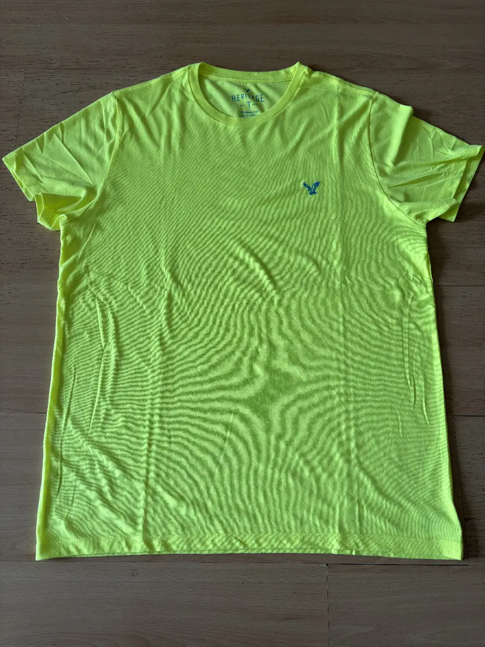 Remera deportiva amarilla de hombre, con logo azul en el pecho. Talle XL, de la marca American Eagle. Ideal para vestir casual.