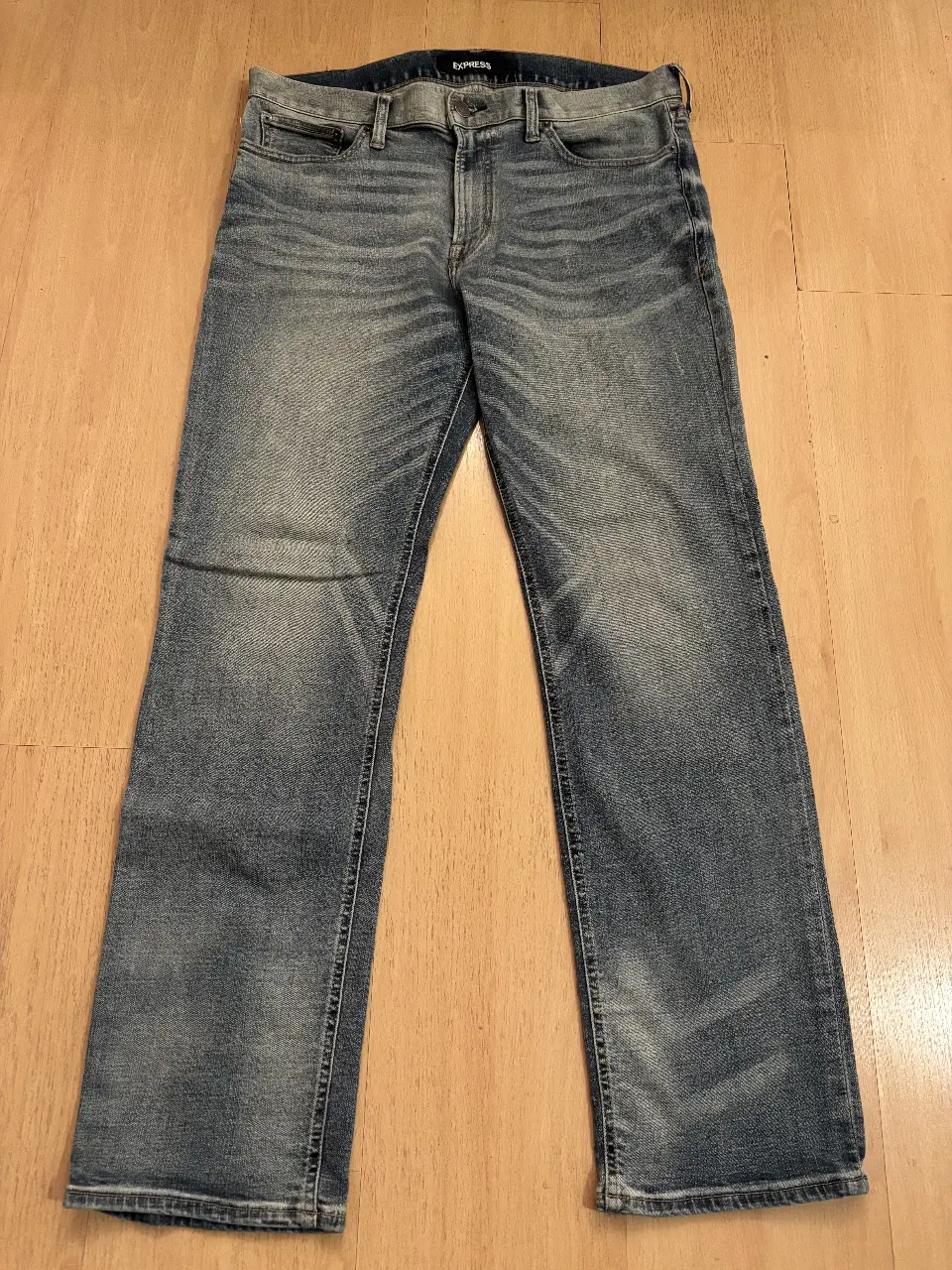Jeans rectos de hombre, color azul gastado, con etiqueta de la marca Express. Talle 34x32. Ideal para un look casual y cómodo.