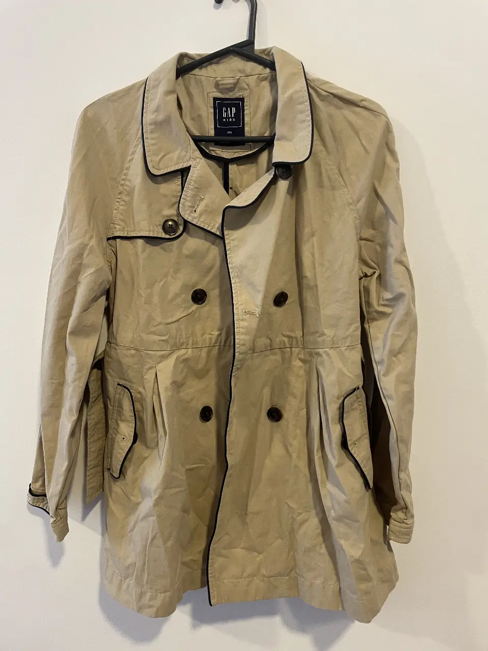 Trench coat GAP color beige con detalles en azul. Ideal para media estación. Posee doble botonadura, cinturón y bolsillos. Es XXL de niña va muy bien para S de mujer.