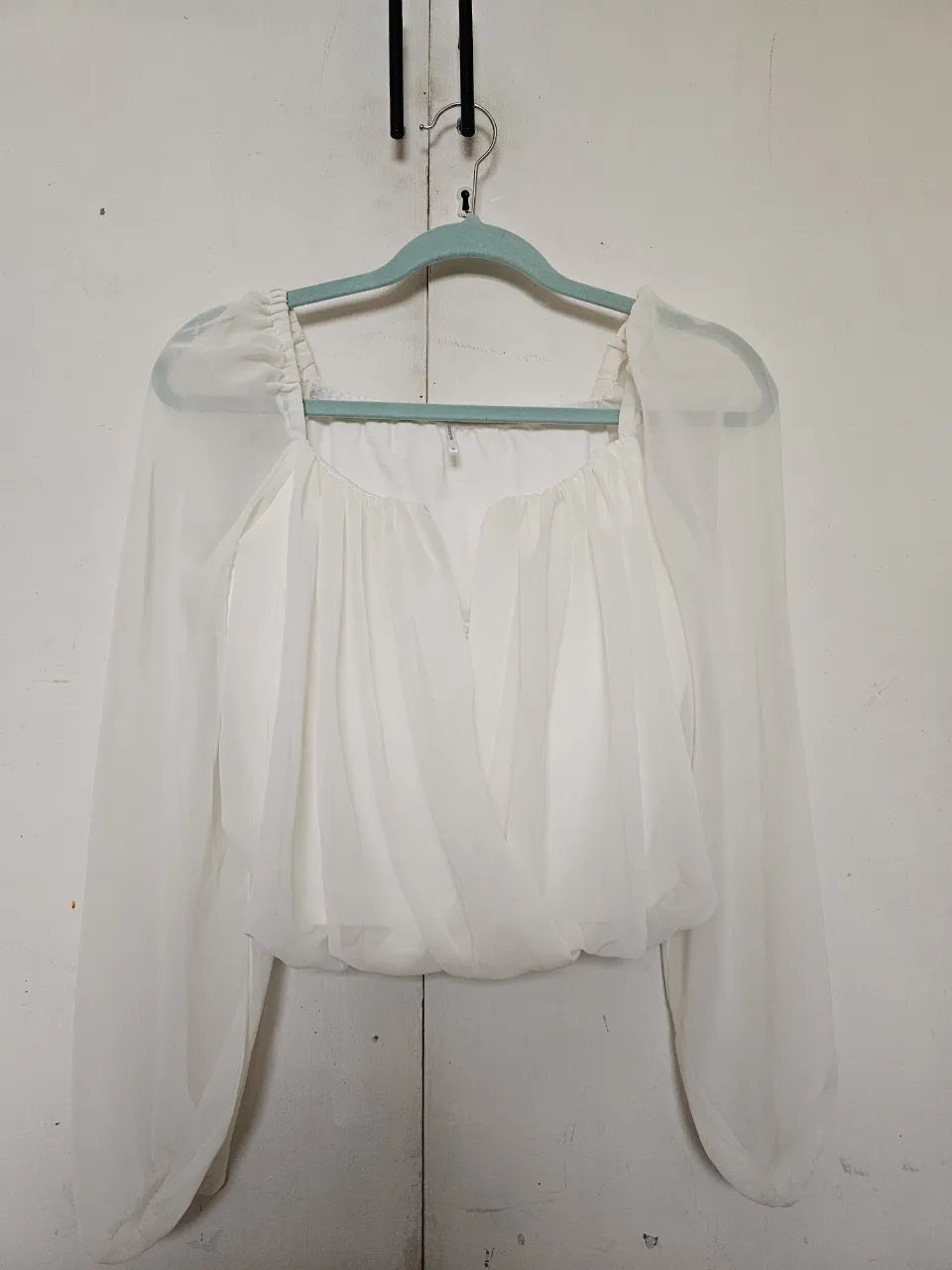 Blusa blanca con mangas largas y detalles drapeados. Ideal para un look elegante y sofisticado.