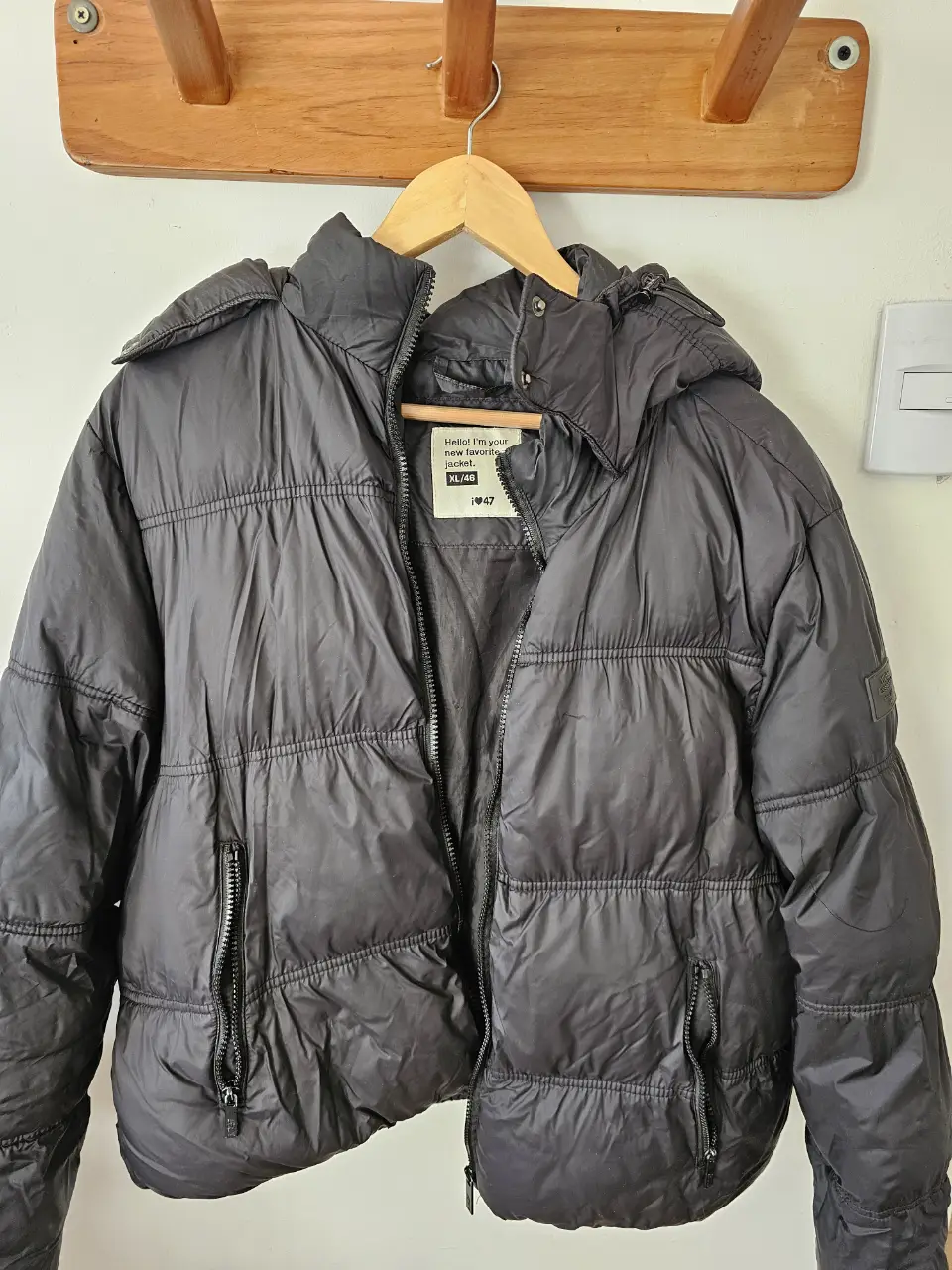 Campera de pluma negra con capucha, ideal para el invierno. Cuenta con cierre y bolsillos.