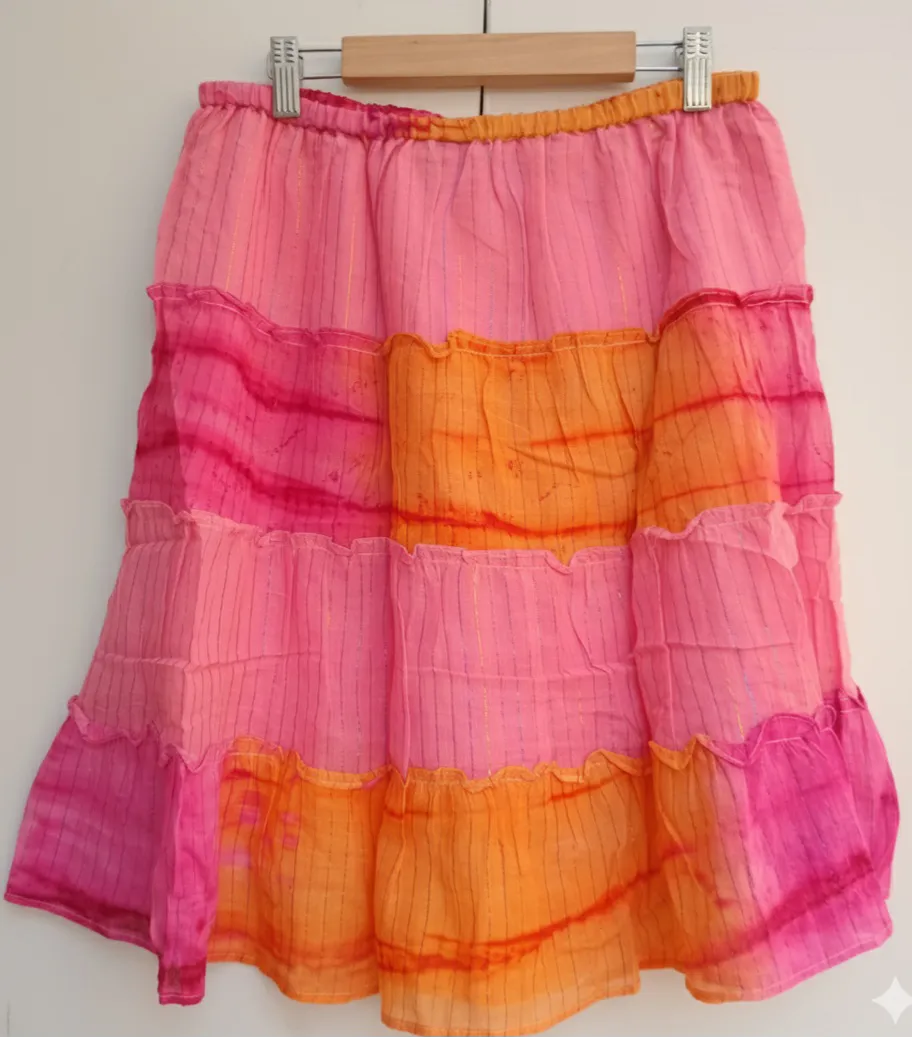 Falda con volados, cintura elastizada y detalles de hilo con brillo. Estampada en tonos vibrantes de rosa y naranja, ideal para un look boho y fresco, super playero. ( se adapta a un S y M)