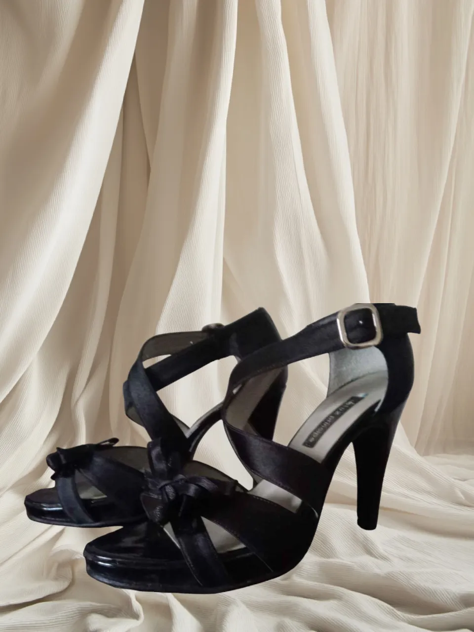 Sandalias de fiesta negras con taco alto. Tienen tiras cruzadas y un detalle de moño en la punta. Perfectas para complementar un look elegante.