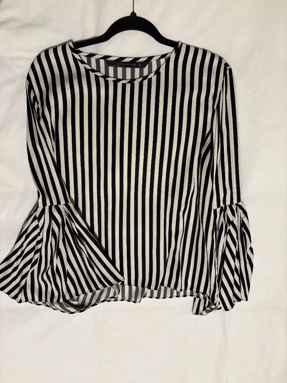 Blusa de mujer a rayas verticales en blanco y negro, con mangas largas acampanadas. Ideal para un look casual y moderno.
