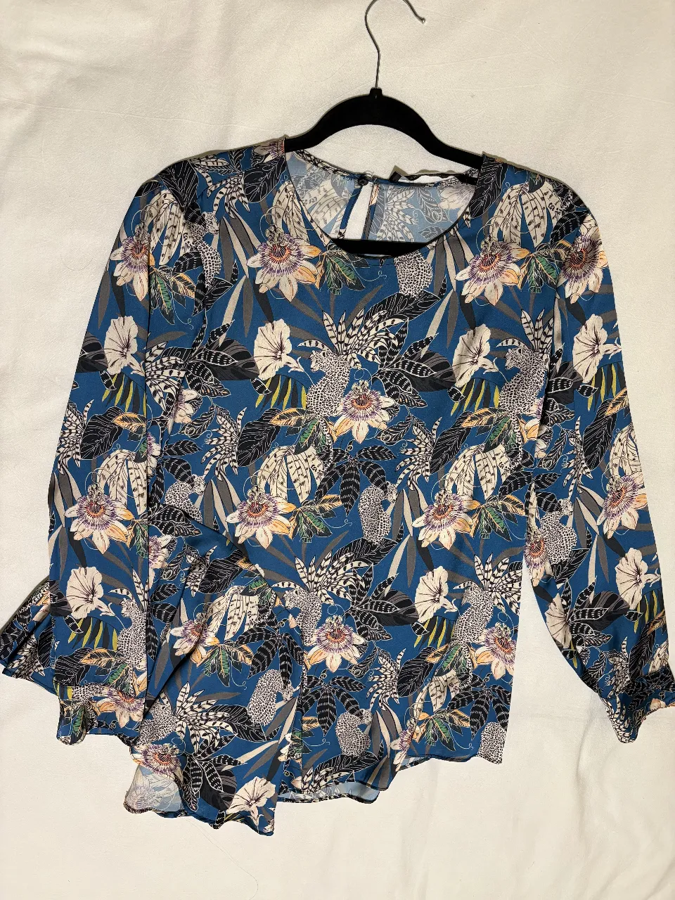 Blusa de mujer con estampado floral en tonos azules, blancos y amarillos. Manga larga con detalle de volados en los puños. Cuello redondo con abertura en la espalda. Marca Carmela Achaval. Talle 2.