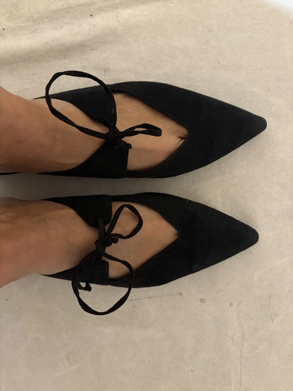 Sandalias de mujer negras con diseño de lazo y punta fina. Marca Mango.