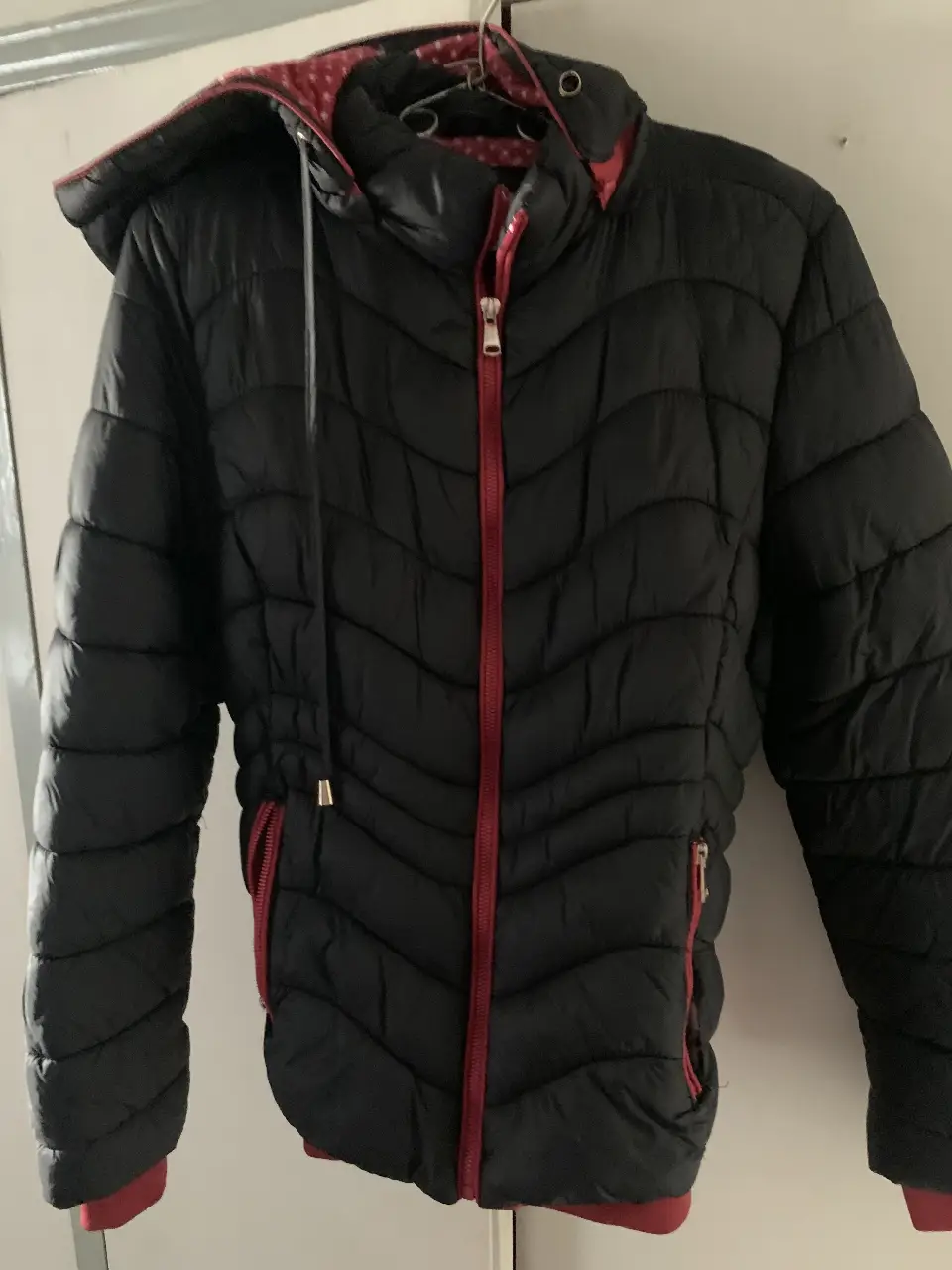 Campera negra acolchada con detalles en rojo. Posee cierre y capucha. Ideal para el invierno.