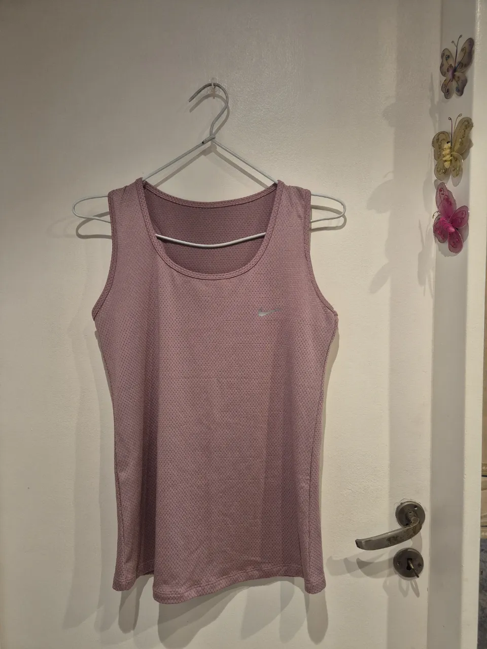 Musculosa deportiva Nike en color rosa pálido, ideal para entrenar o para un look casual y cómodo. Su diseño es ligero y transpirable, perfecta para mantenerte fresca durante la actividad física.
