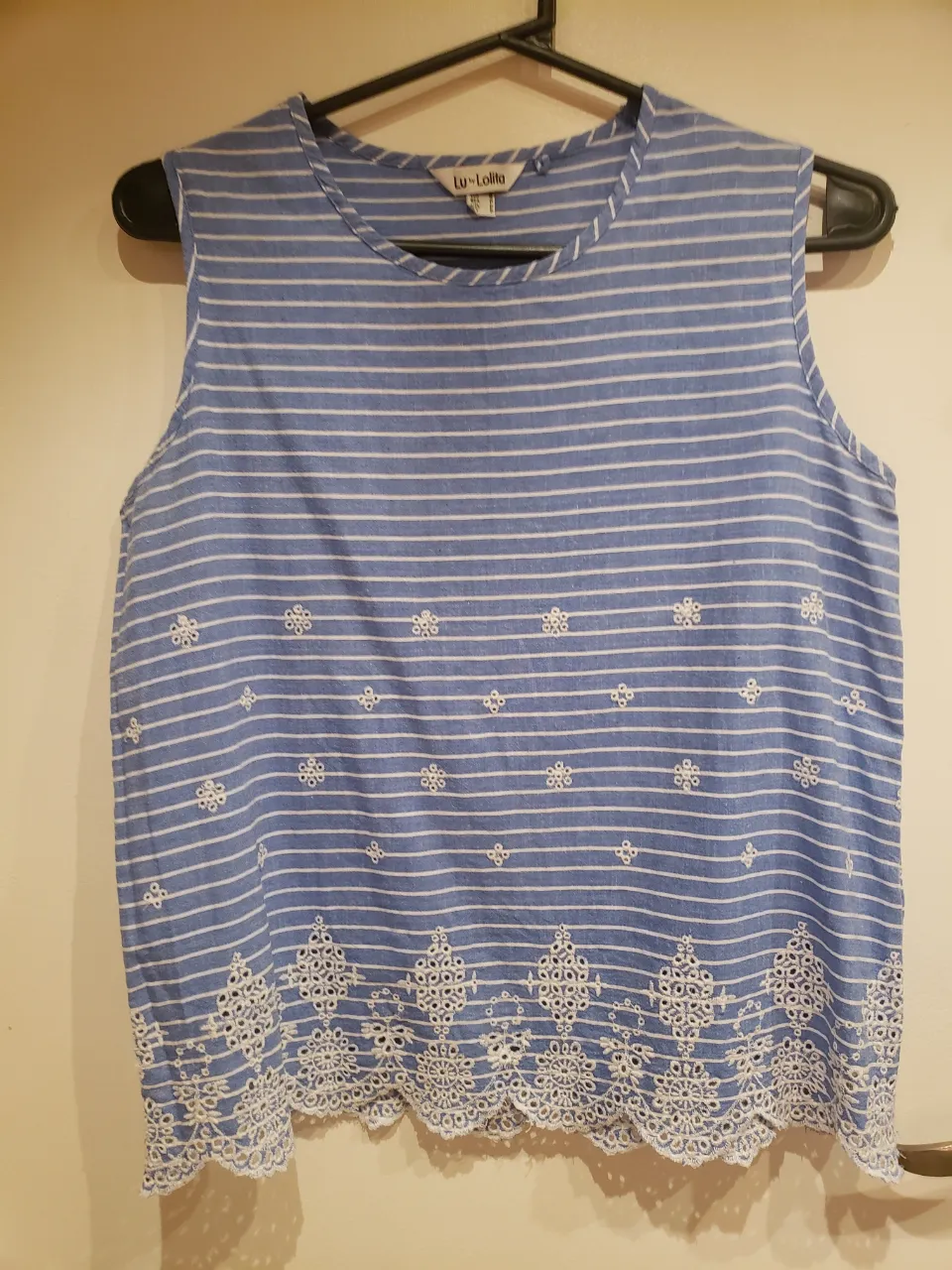 Remera de algodón a rayas celestes y blancas, sin mangas, con detalles de bordado y puntilla en la parte inferior. Ideal para un look fresco y casual.