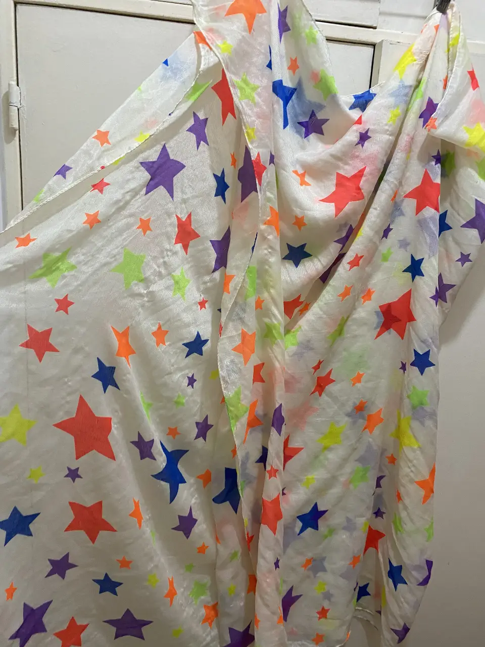 Pañuelo de tela con estampado de estrellas de colores. Ideal para usar en la playa o como accesorio de moda.