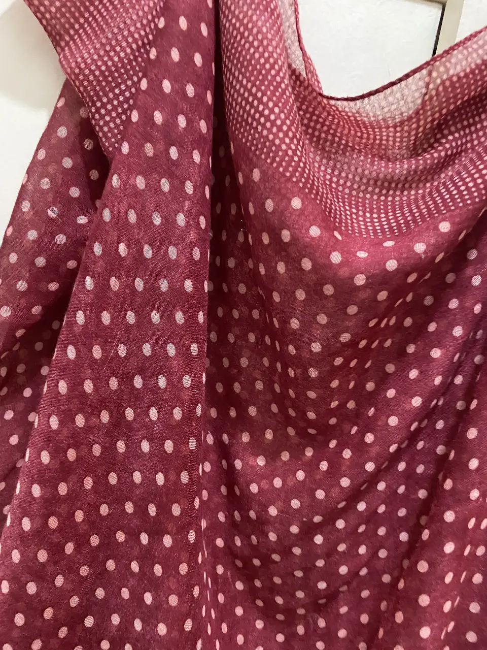 Pañuelo de gasa con estampado de lunares blancos sobre fondo rojo. Ideal para complementar cualquier look, ligero y versátil.