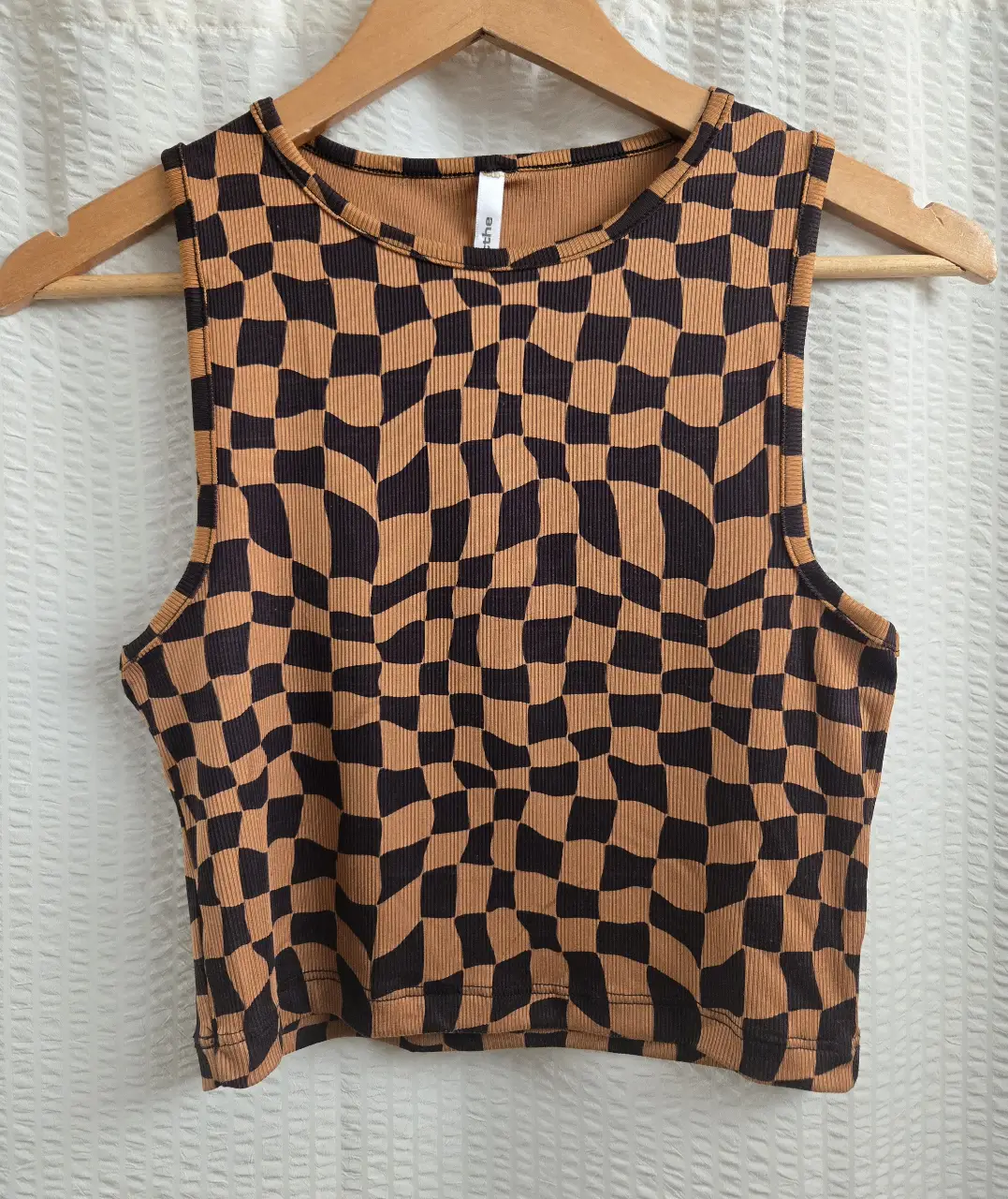 Top sin mangas con estampado en tonos marrones y naranjas. Corte crop. En la espalda tiene un leve desgaste de la tela debido al uso de cartera. 94% poliester 6% elastano