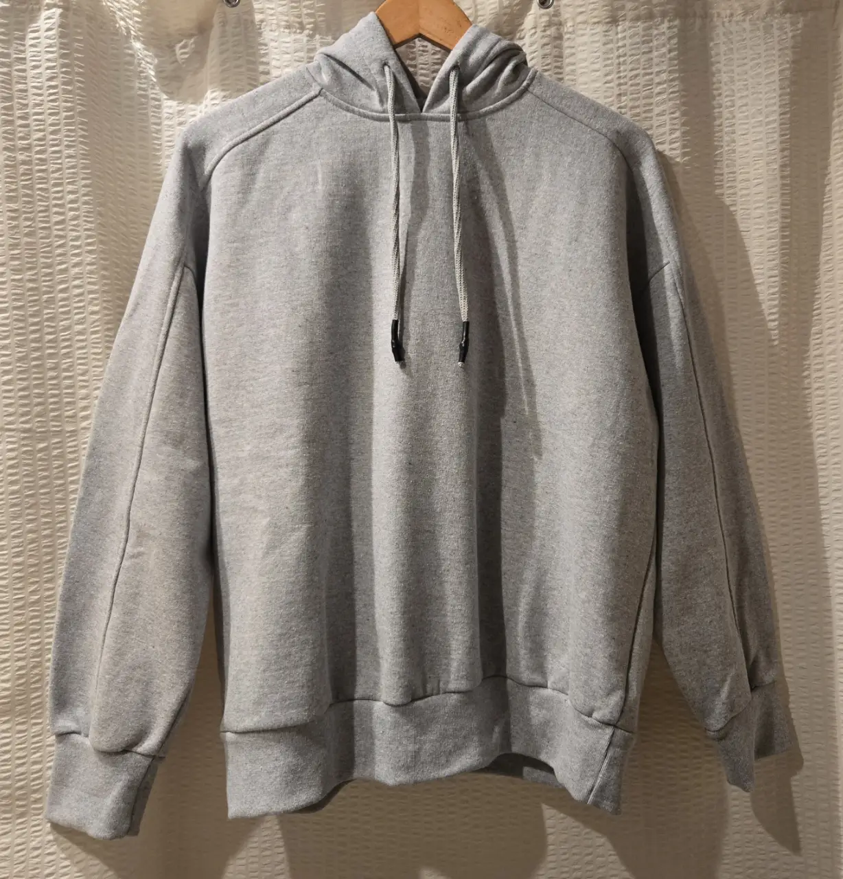 Buzo color gris melange, con capucha y cordones. Terminaciones en rib. 50% algodón 50% fibra reciclada