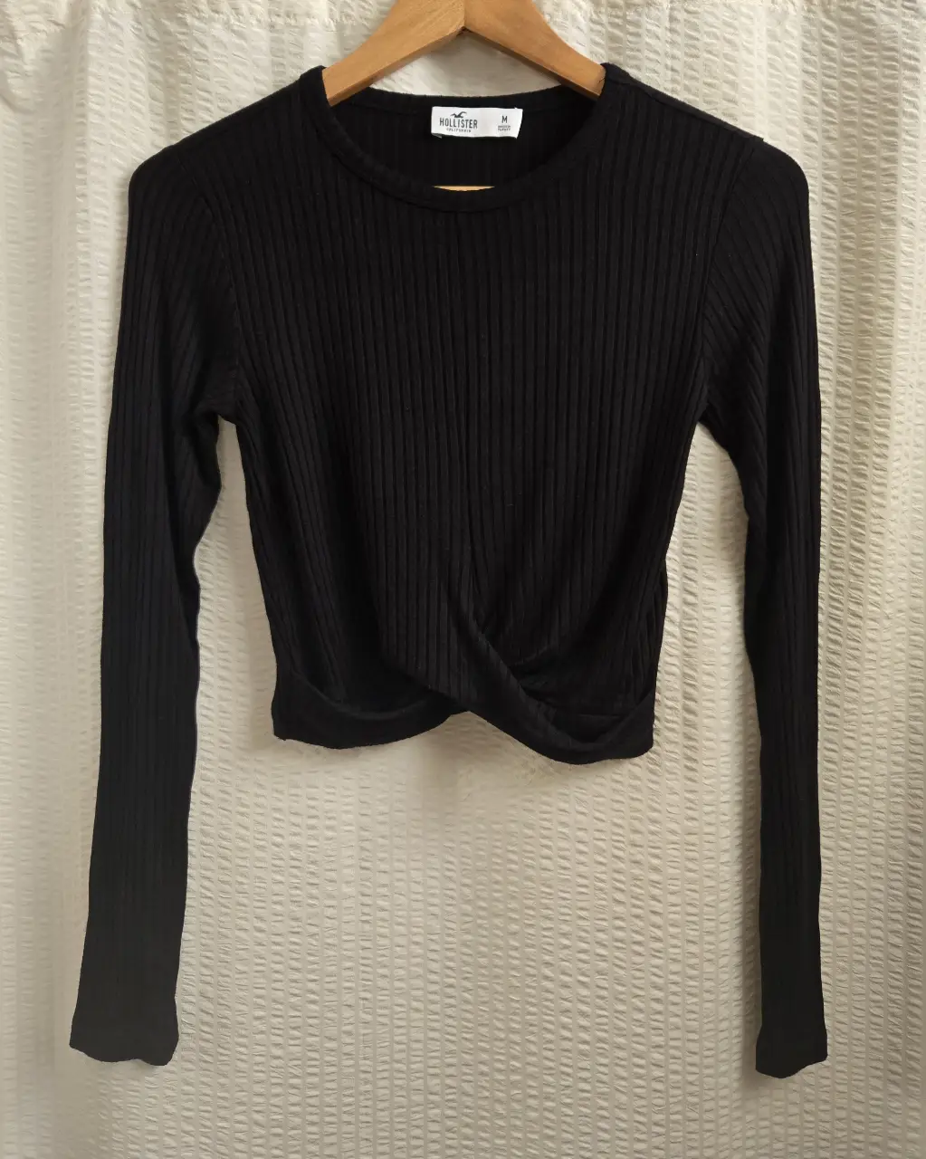 Remera manga larga negra de la marca Hollister, con detalle de cruce en la cintura. Corte crop. Morley ancho. 93% viscosa 7% elastano