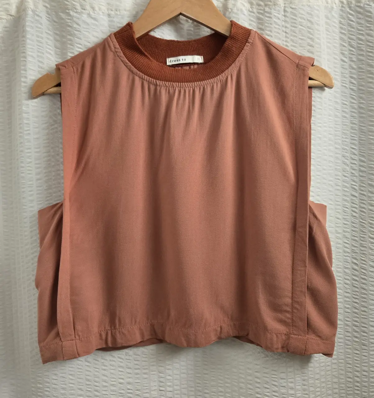 Top sin mangas de crepe. Color naranja/salmón con cuello tejido en color marrón. 100% viscosa
