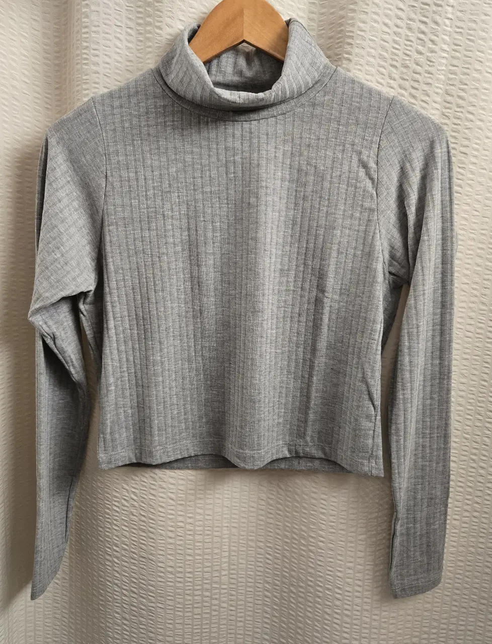 Remera de cuello alto, manga larga y corte crop. Confeccionada en tejido de punto acanalado, suave y cómodo. Talle L pero equivale a S/M. 65% algodón 35% poliester