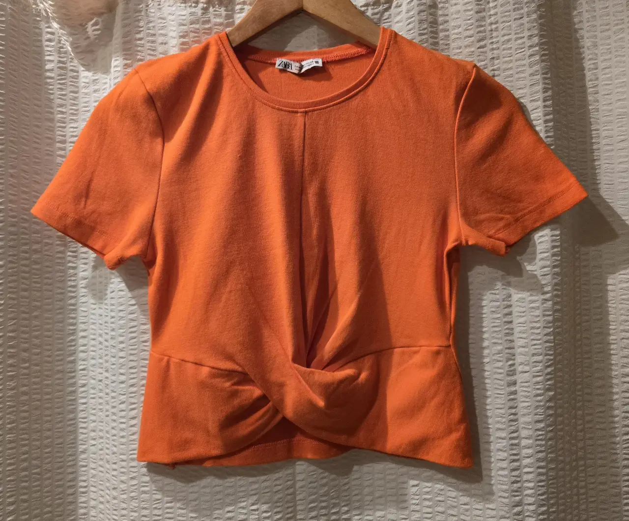 Remera naranja, manga corta, con detalle de nudo en la parte delantera. 95% algodón 5% elastano