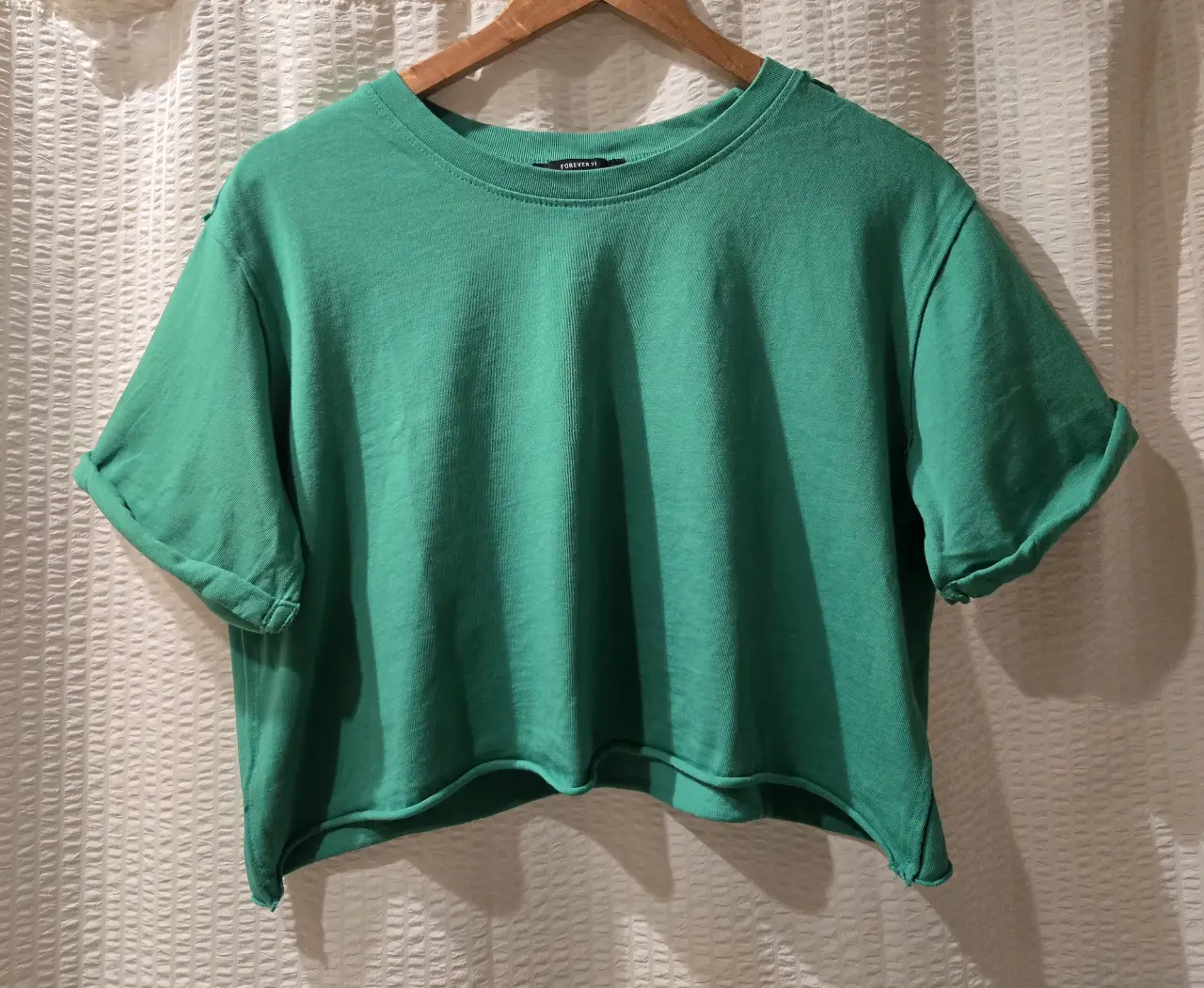 Remera crop de jersey de algodón verde, con mangas cortas dobladas y corte recto. 100% algodón 