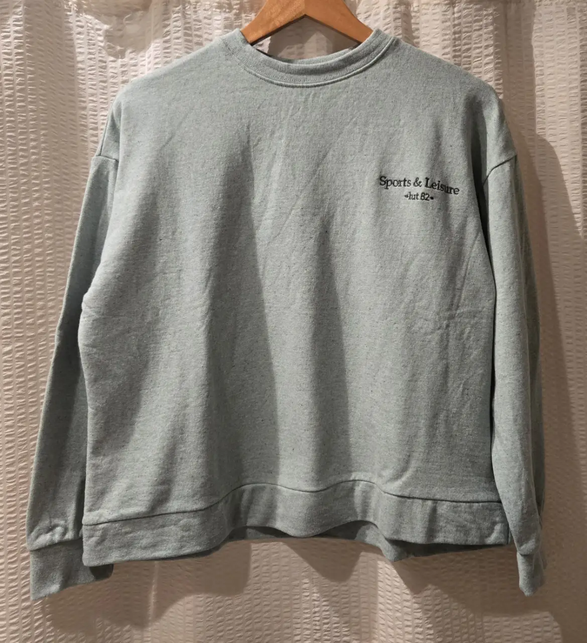 Buzo de cuello redondo verde menta, con bordado "Sports & Leisure". Ideal para un look casual y cómodo. 50% algodon 50% fibra reciclada