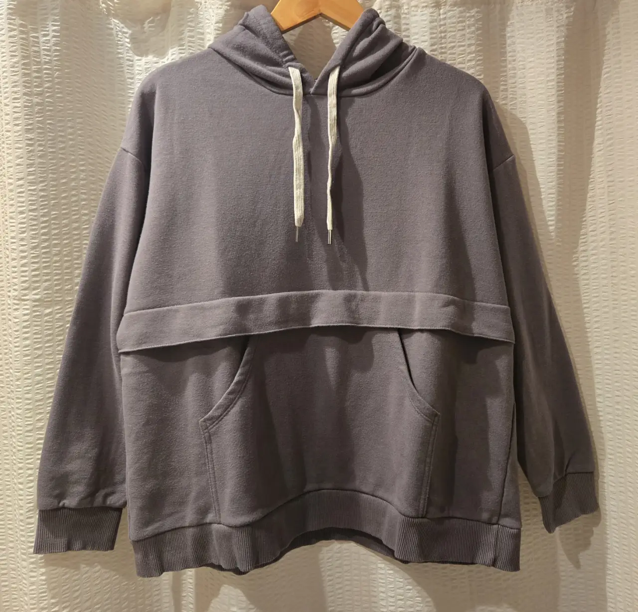 Buzo canguro de color gris, de frisa, con bolsillo delantero y capucha. Ideal para un look casual y cómodo. 50% algodon 50% fibra reciclada