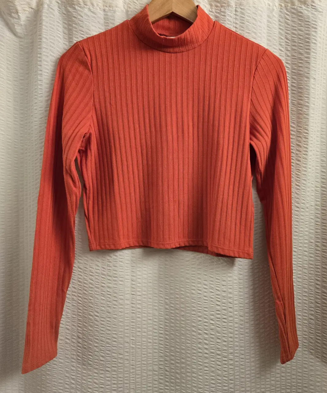 Remera manga larga de cuello alto, de color naranja. Confeccionada en un tejido acanalado que le da un toque de textura y estilo. 72% poliester 22% viscosa 5% elastano. Talle M pero equivale a S