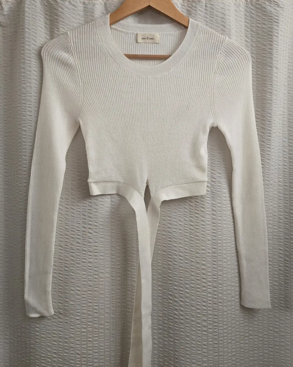 Sweater liviano color crudo con mangas largas y detalle de tiras para atar en la cintura. 95% algodón 5% cashmere
