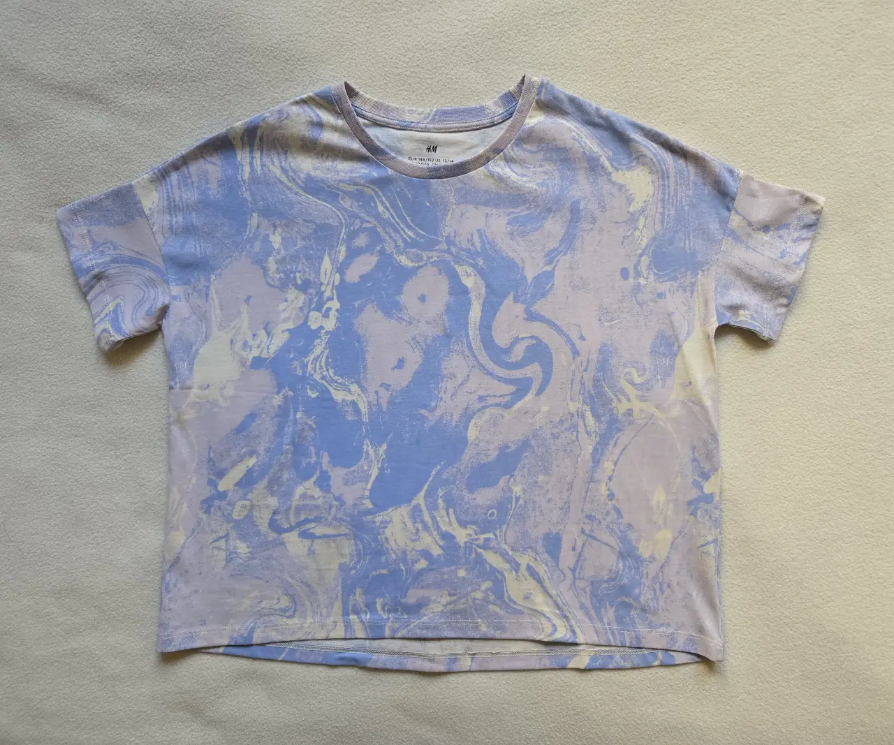 Remera manga corta con estampado en tonos lilas y celestes, en el frente y la espalda. Talle 10/12 pero equivale a un S de mujer