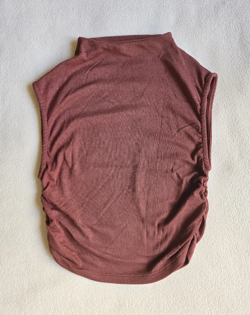 Top sin mangas de color marrón con detalle fruncido en los laterales. Cuello alto. Talle M pero va para un S tambien. Morley 96% viscosa 4% elastano