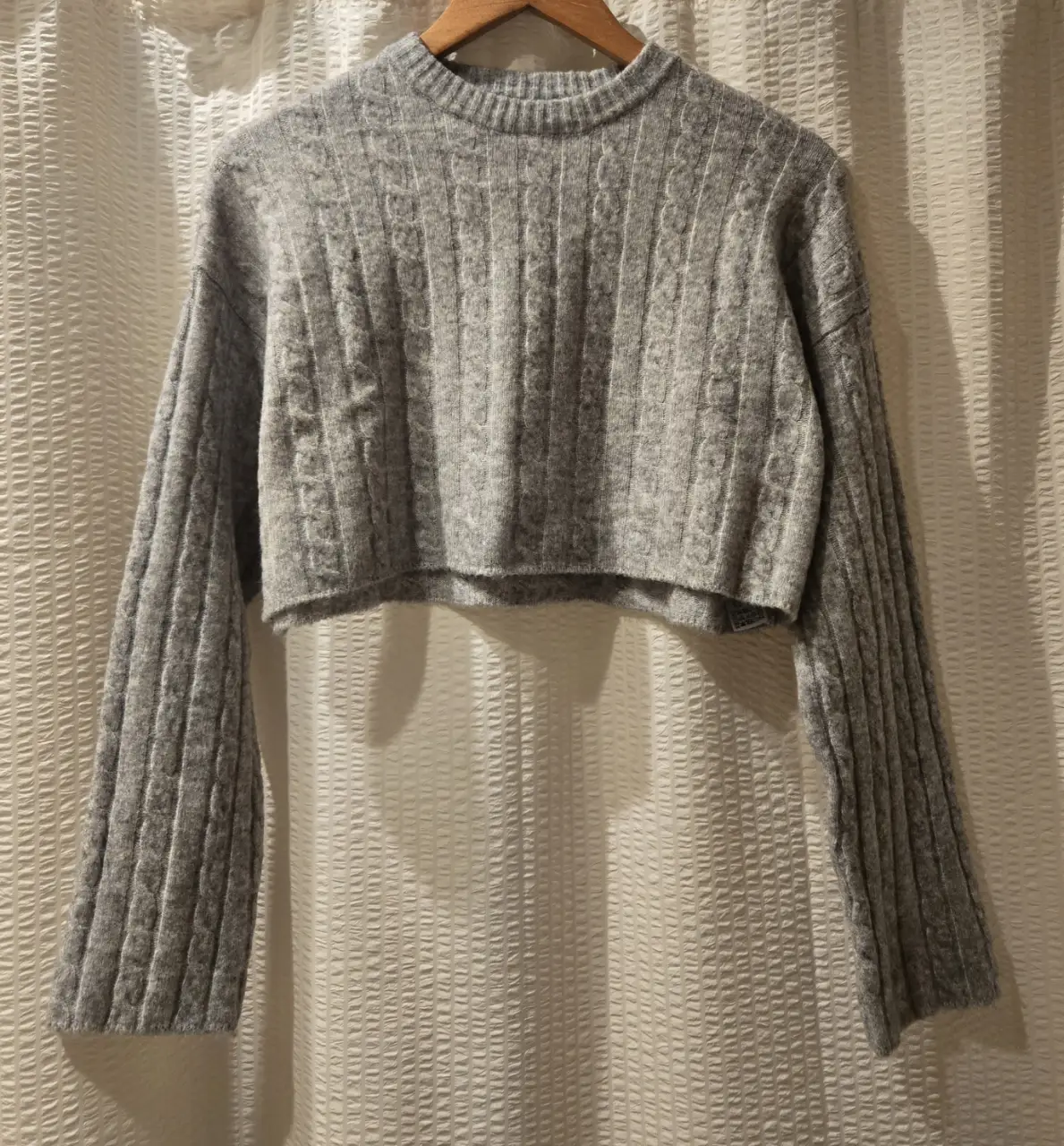 Sweater crop gris de Bershka, con diseño de trenzas y mangas largas. Ideal para un look casual y canchero. Largo a la cintura, ancho. 94% poliester 6% elastano