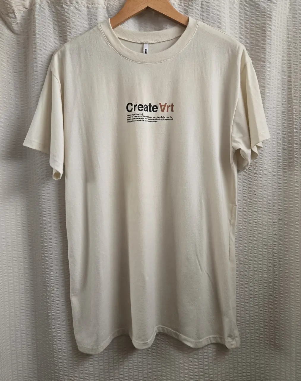 Remera unisex de color crudo con estampado "create art" en el frente. Largo debajo de la cadera. Confeccionada en algodón suave. 100% algodón
