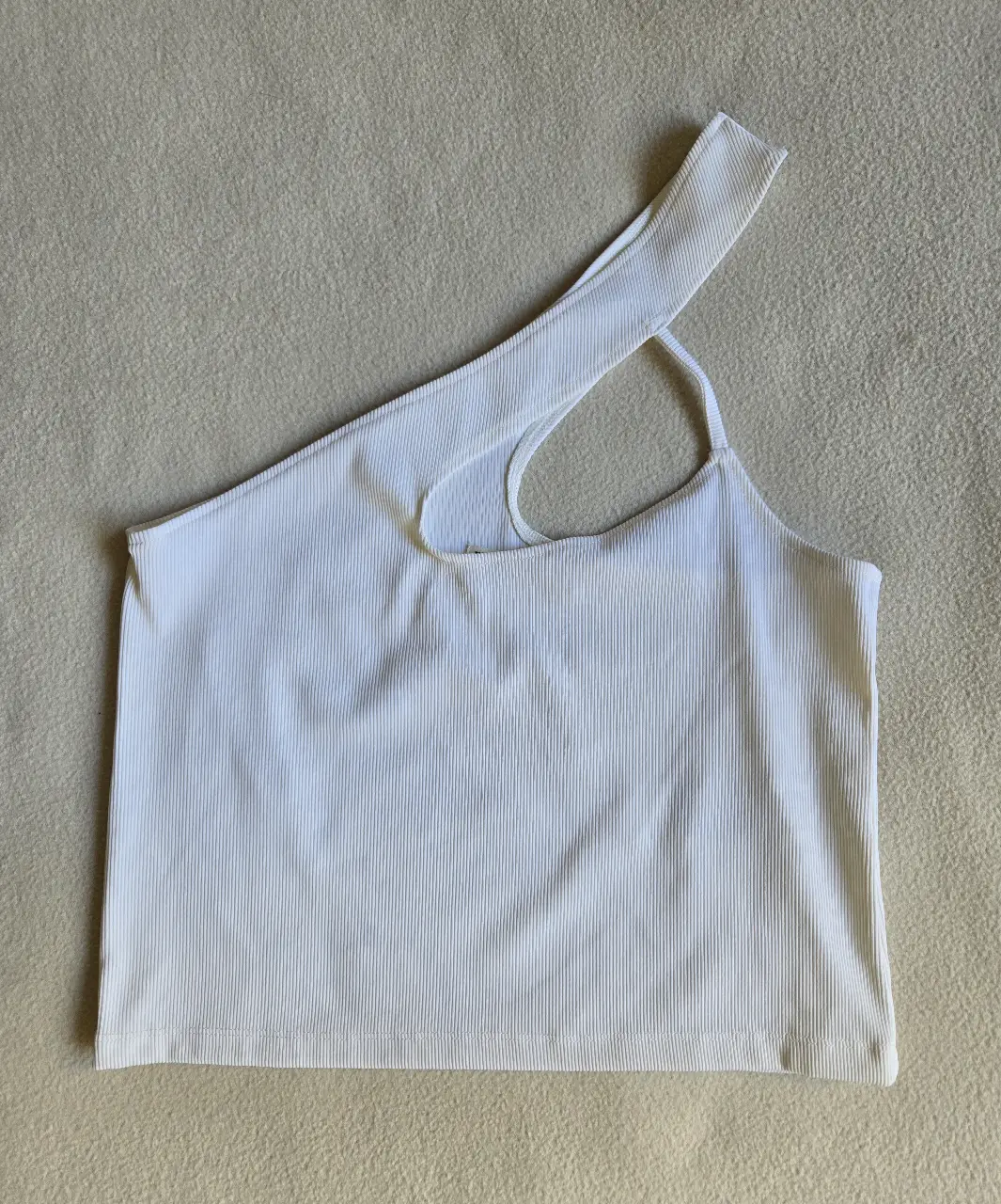 Top blanco escocte asimétrico con un solo hombro y detalle de abertura. Morley 88% poliamida 12% elastano. Talle M pero va bien para S