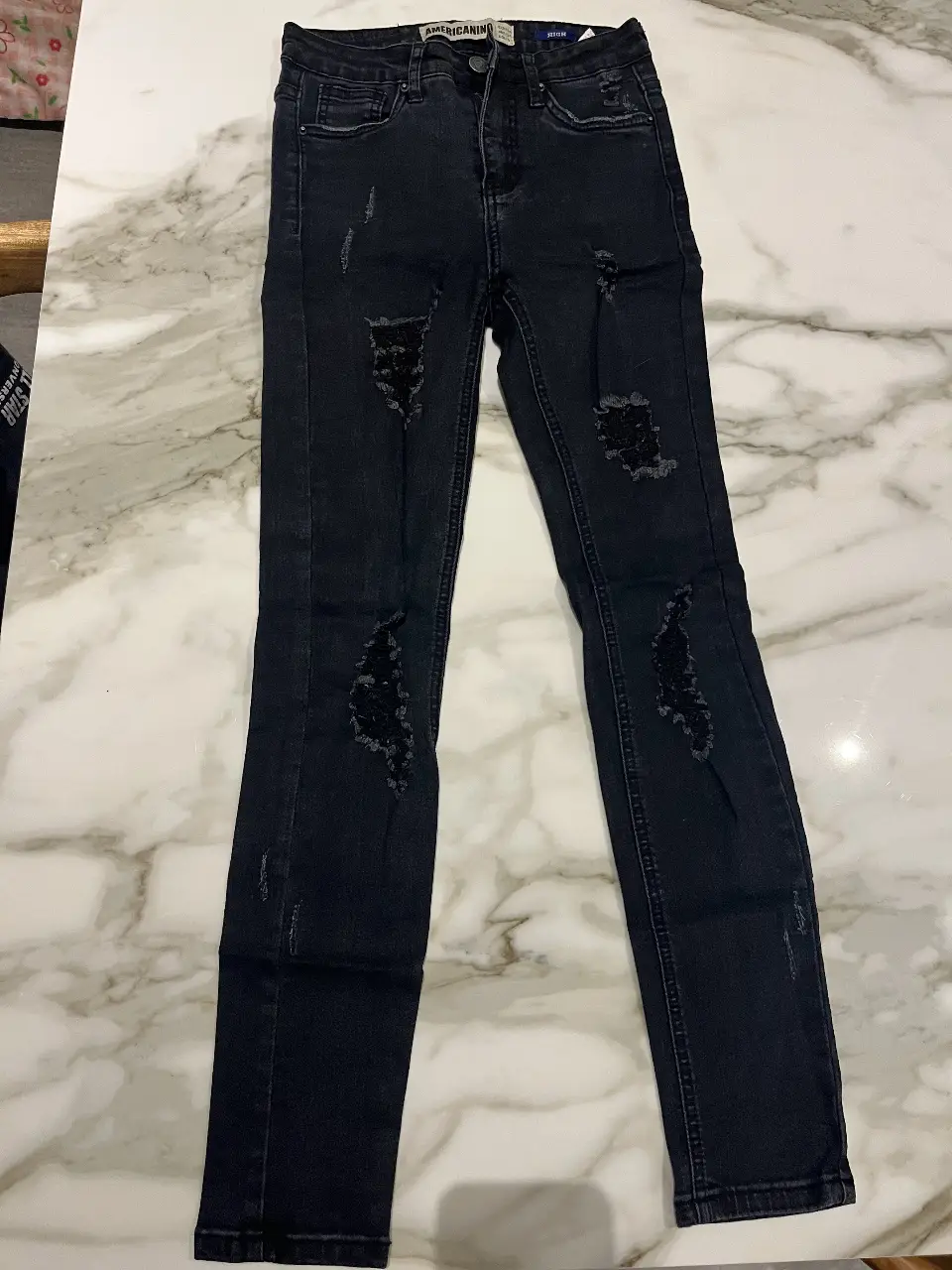 Jeans negro de mujer, tiro medio, con roturas en las rodillas. Marca Americanino. Ideal para un look casual y moderno.