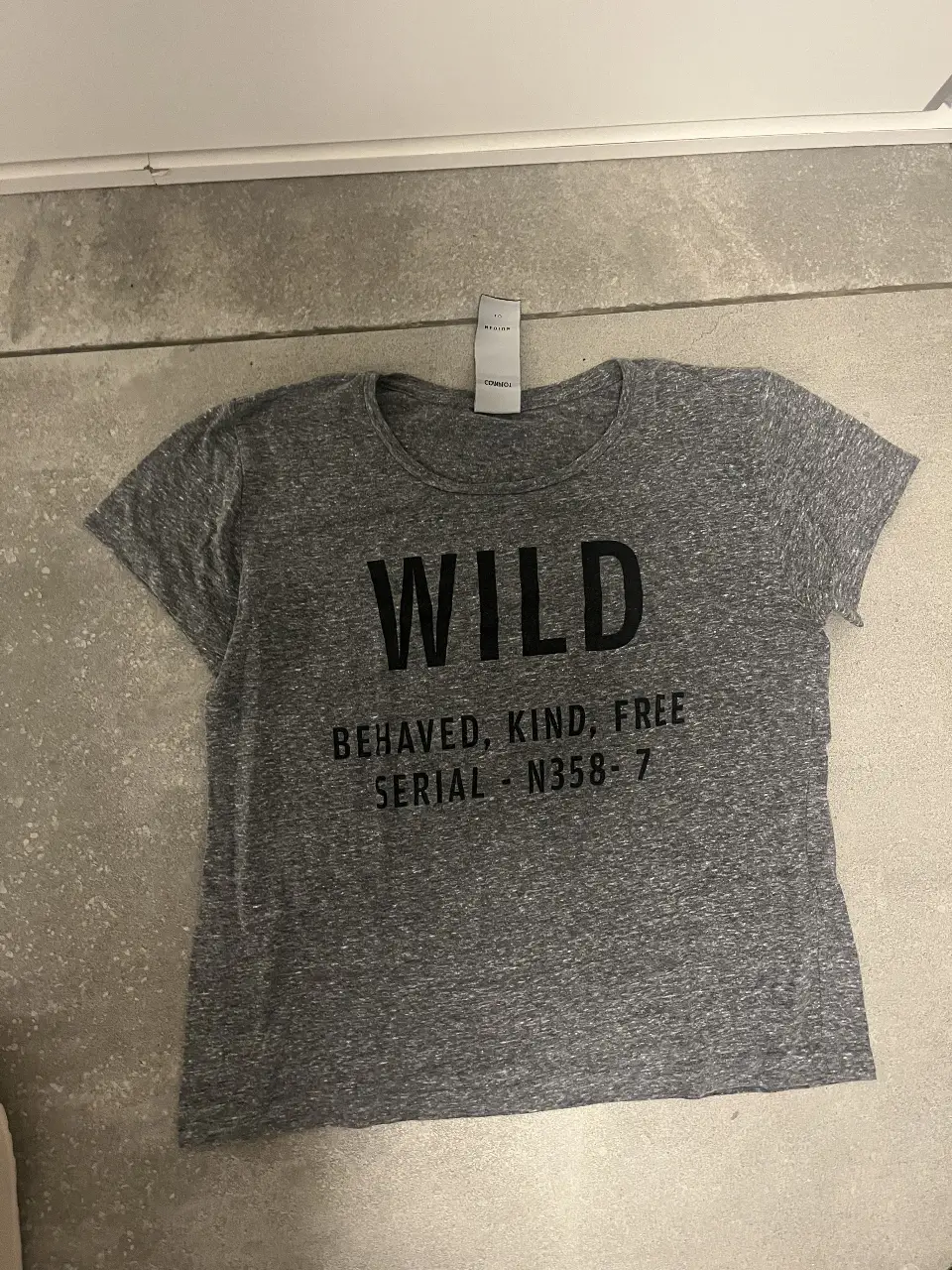 Remera de algodón gris con estampado "WILD" y la frase "BEHAVED, KIND, FREE". Ideal para un look casual y cómodo.