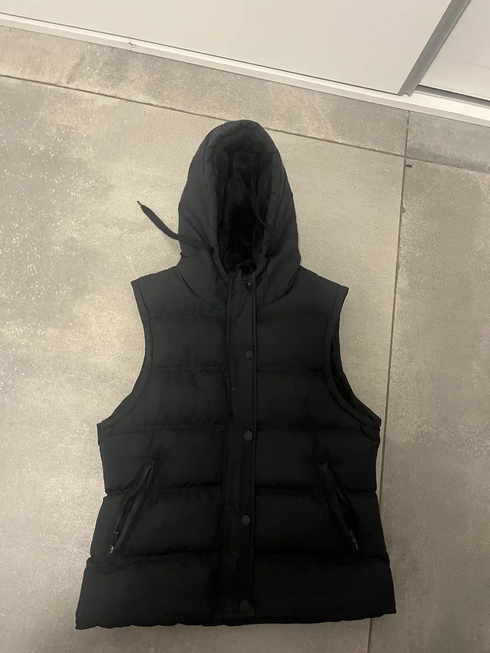 Chaleco negro con capucha, abrigado y cómodo. Ideal para el invierno. Cuenta con cierre y bolsillos.