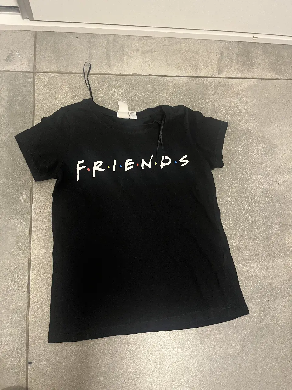 Remera negra de manga corta con estampado del logo de la serie Friends. Talle XS, ideal para un look casual y cómodo.
