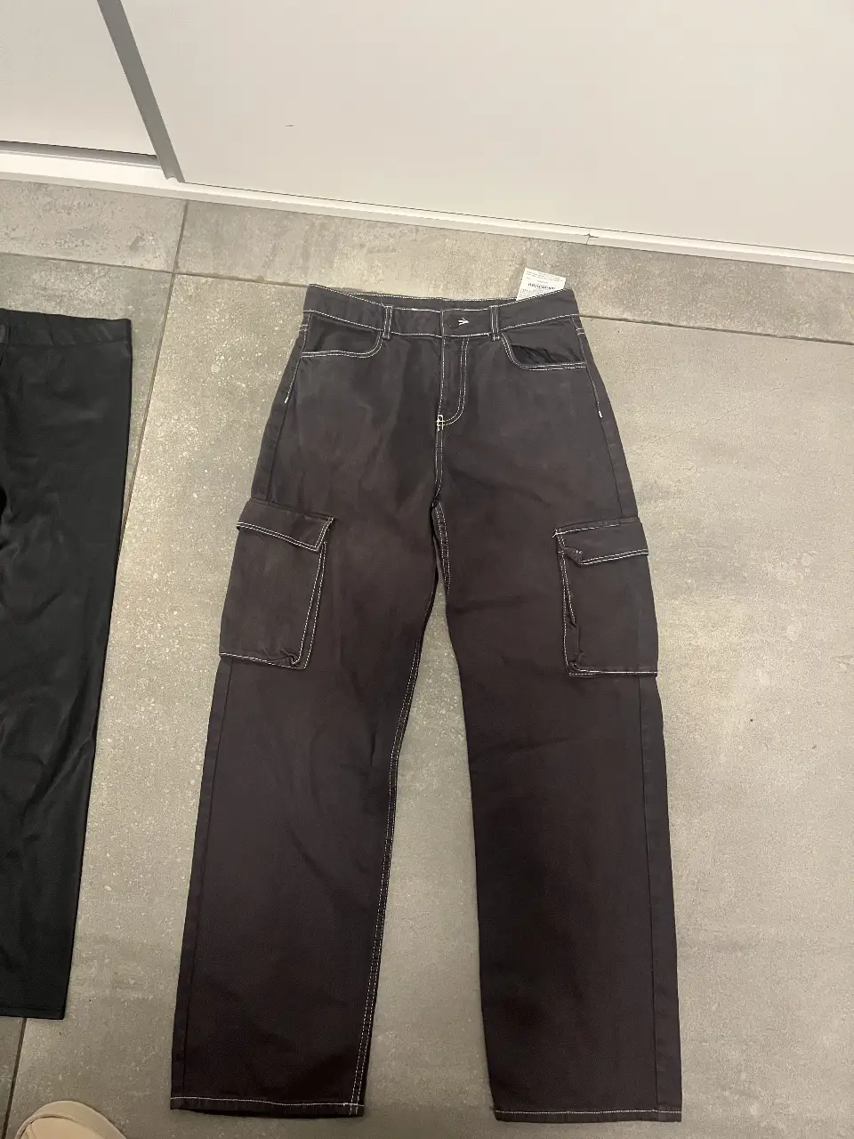 Pantalón cargo negro con detalles de costura en blanco. Tiro medio, con bolsillos laterales amplios y corte recto. Ideal para un look casual y moderno.