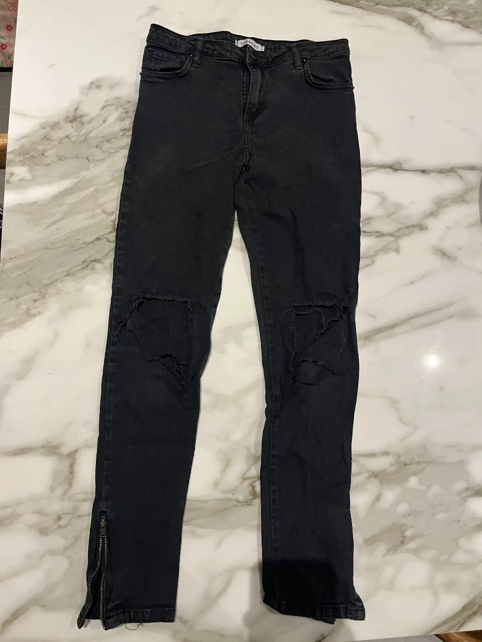 Jeans negro de mujer con roturas en las rodillas y cierre en los tobillos. Talle 42.