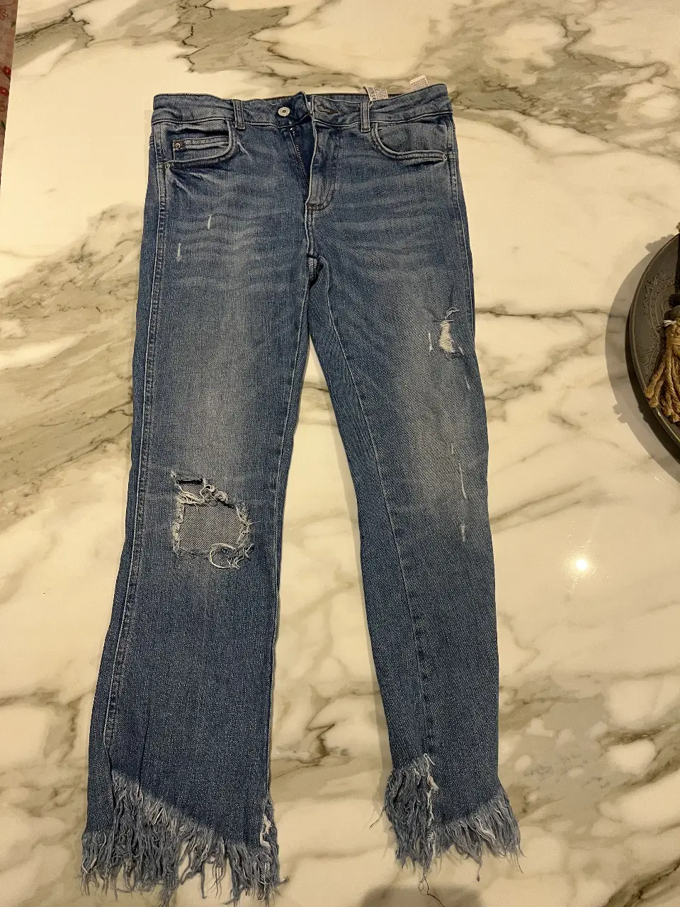 Jeans de mujer de la marca Zara, modelo "TRF blue collection", con roturas en las rodillas y flecos en los bajos. 