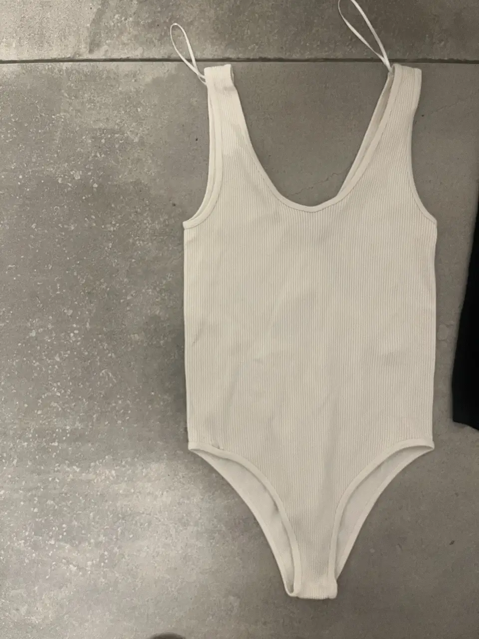 Body blanco de mujer, de tela acanalada, con escote en V y tiras finas. Ideal para un look casual y cómodo.