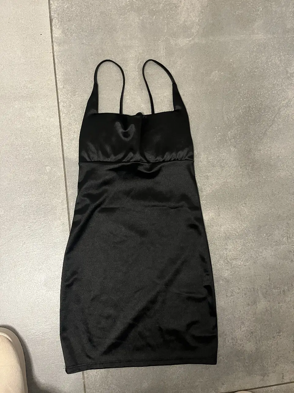 Vestido mini negro de satén, con tirantes finos y escote cuadrado. Ideal para una salida nocturna o evento especial.