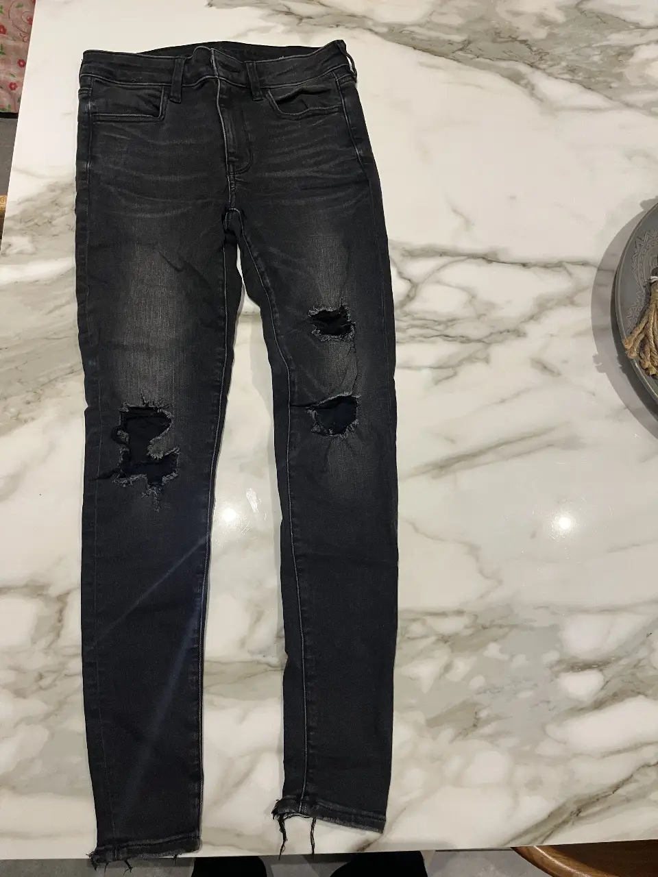 Jeans negro de mujer, tiro alto, con roturas en las rodillas. Marca American Eagle, talle 2 regular.