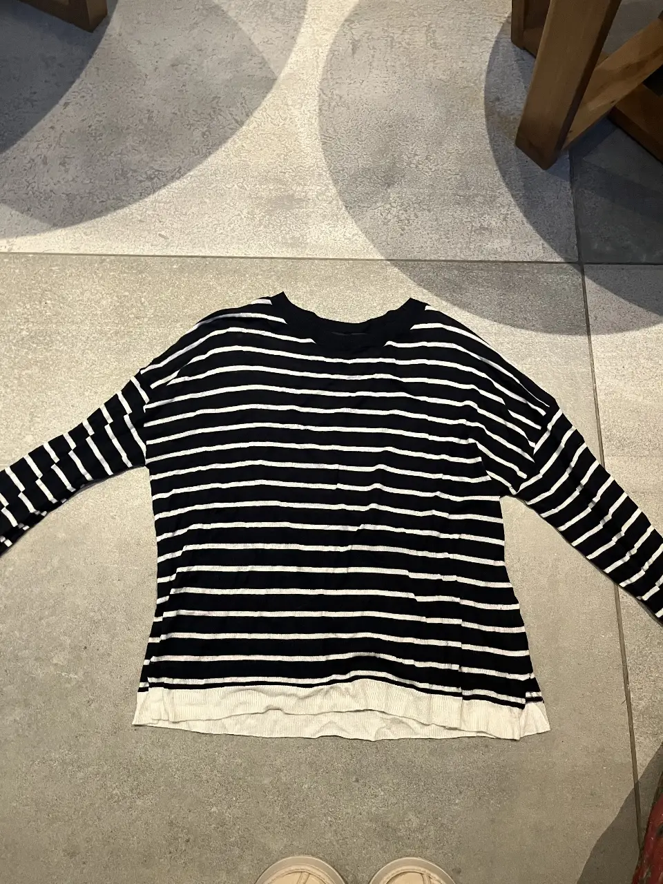 Sweater de punto a rayas horizontales en blanco y negro, con cuello en V. Ideal para un look casual y cómodo.