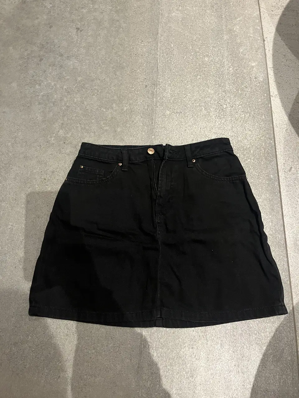 Minifalda de jean negra de la marca H&M Divided, talle 6. Ideal para un look casual y versátil.