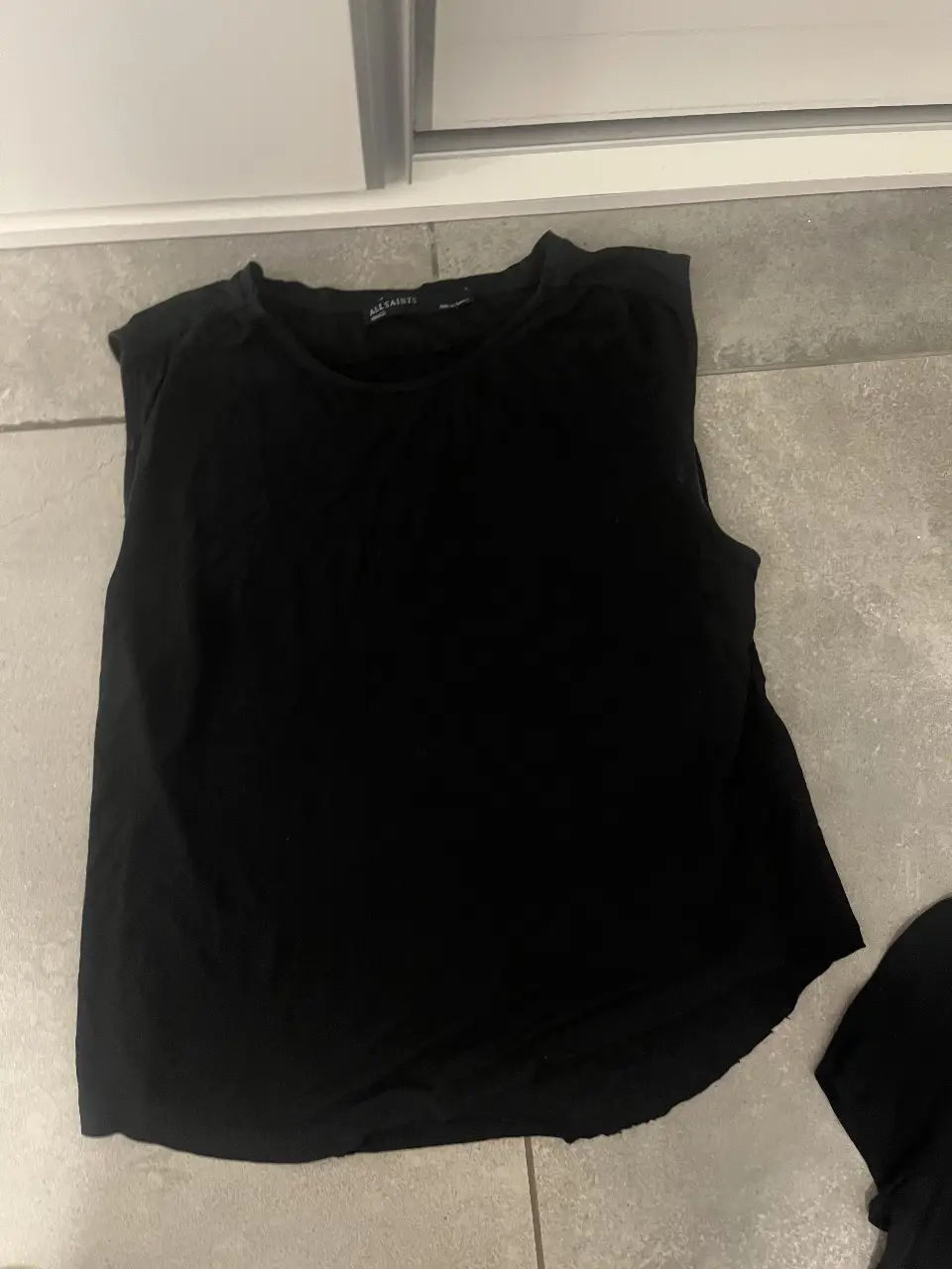 Musculosa negra de la marca AllSaints, ideal para un look casual y cómodo. Perfecta para combinar con jeans o shorts.